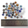 Assorted colored glass beads with a ruler for scale on a white background