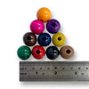 A variety of multicolored wooden beads, each with a hole for stringing, displayed next to a ruler for scale.