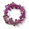 A wired star garland made up of pale pink colored star-shaped elements coiled into a circle on a white background.