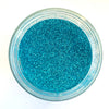 A top-down view of a clear round jar filled with bright aqua blue glitter on a white background.